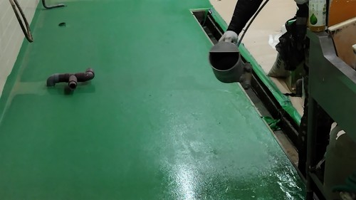 合志市の旅館厨房で床塗装に滑り止め材を施工する様子