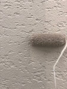 合志市の外壁塗装工事で中塗り作業を行っている様子