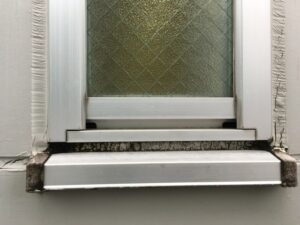 サッシ下部のコーキングが硬化し黒ずみが発生した状態（菊池郡 建物）